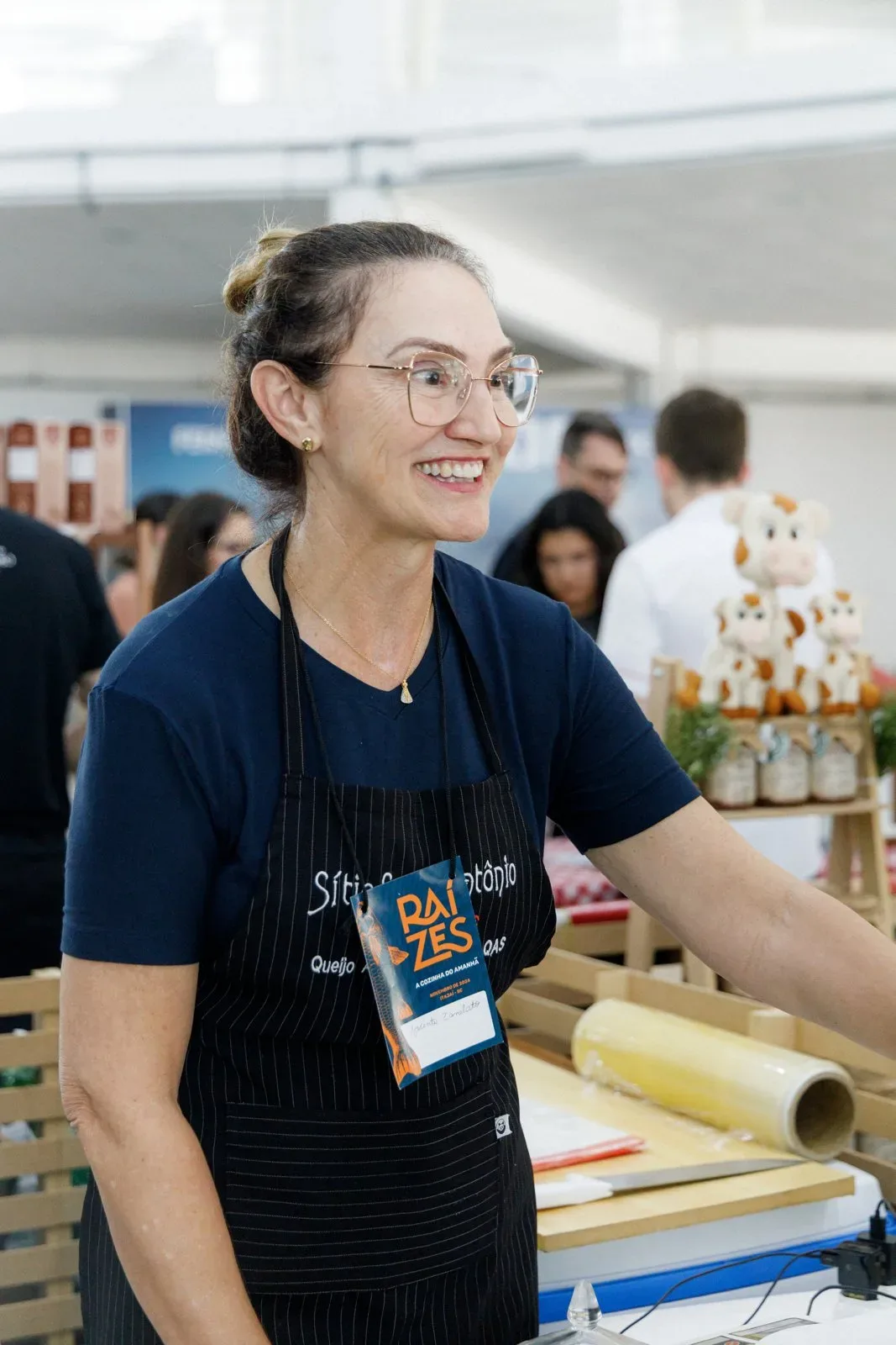 Produtora sorrindo atrás da sua banca, na Feira